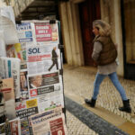 A woman passes by a newspaper stand, a day after Portugal's President Marcelo Rebelo de Sousa announced his decision to dissolve parliament triggering snap general elections on March 10th 2024, in Lisbon